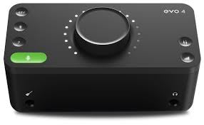 Black audio interface with a large knob and green power button on a white background