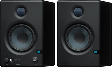 Pair of black studio monitors with visible brand logo on a white background